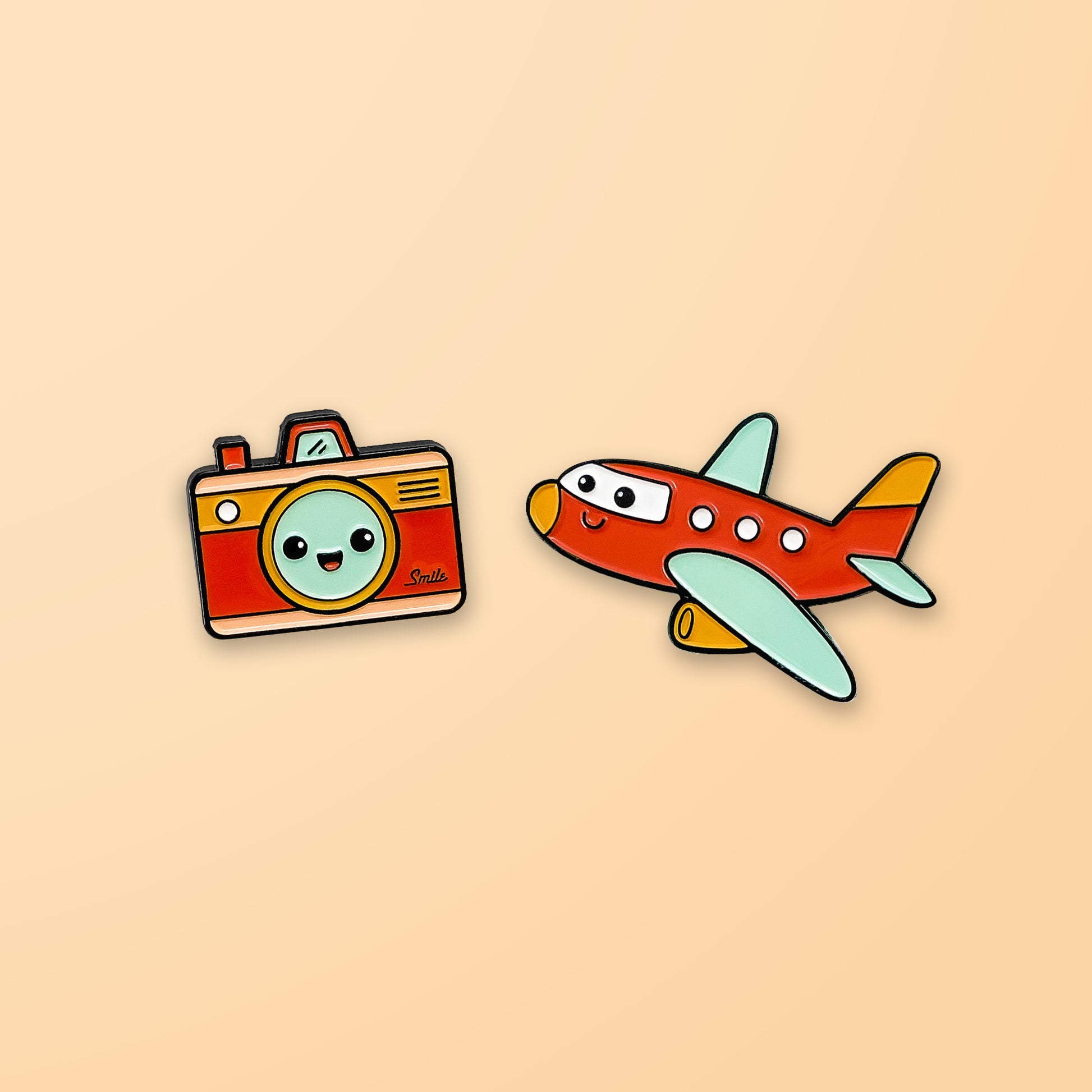 Camera and Plane enamel pins on peach background