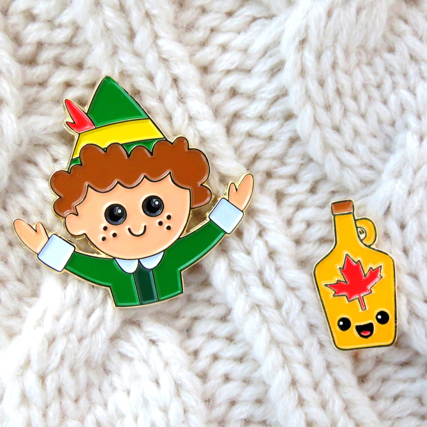 Buddy the Elf and Maple Syrup enamel pin set on cream color knitted sweater