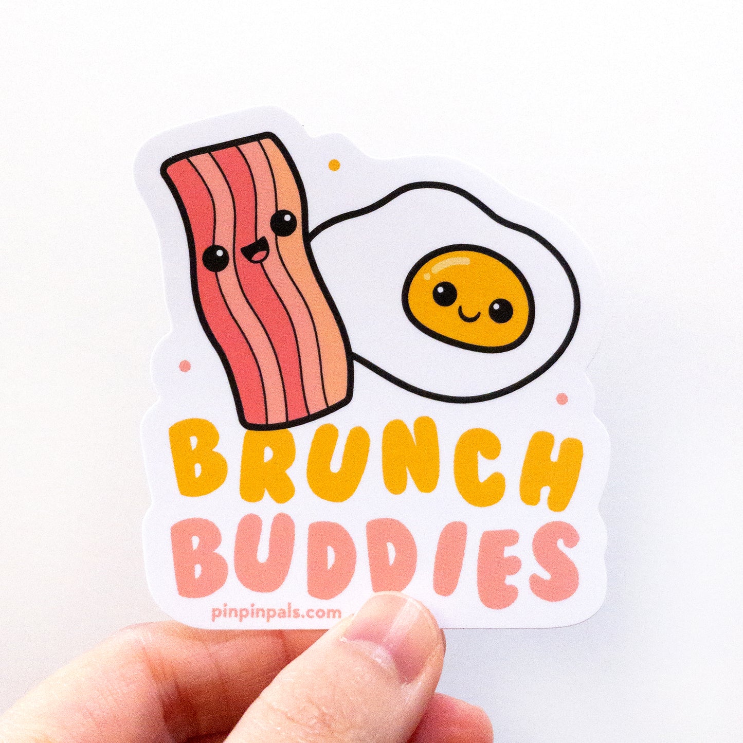 Hand holding a Brunch Buddies - egg and bacon vinyl sticker