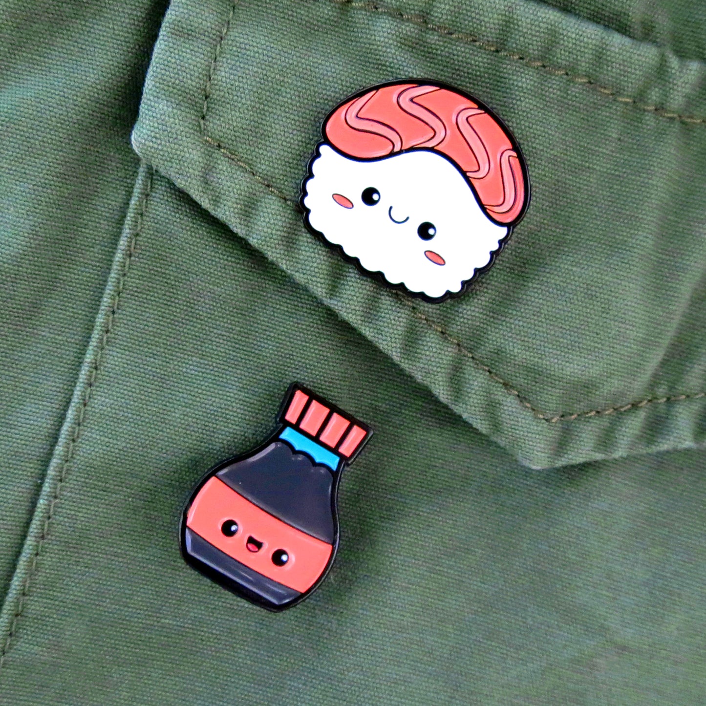 Sushi and Soy Sauce enamel pins on olive green canvas jacket pocket